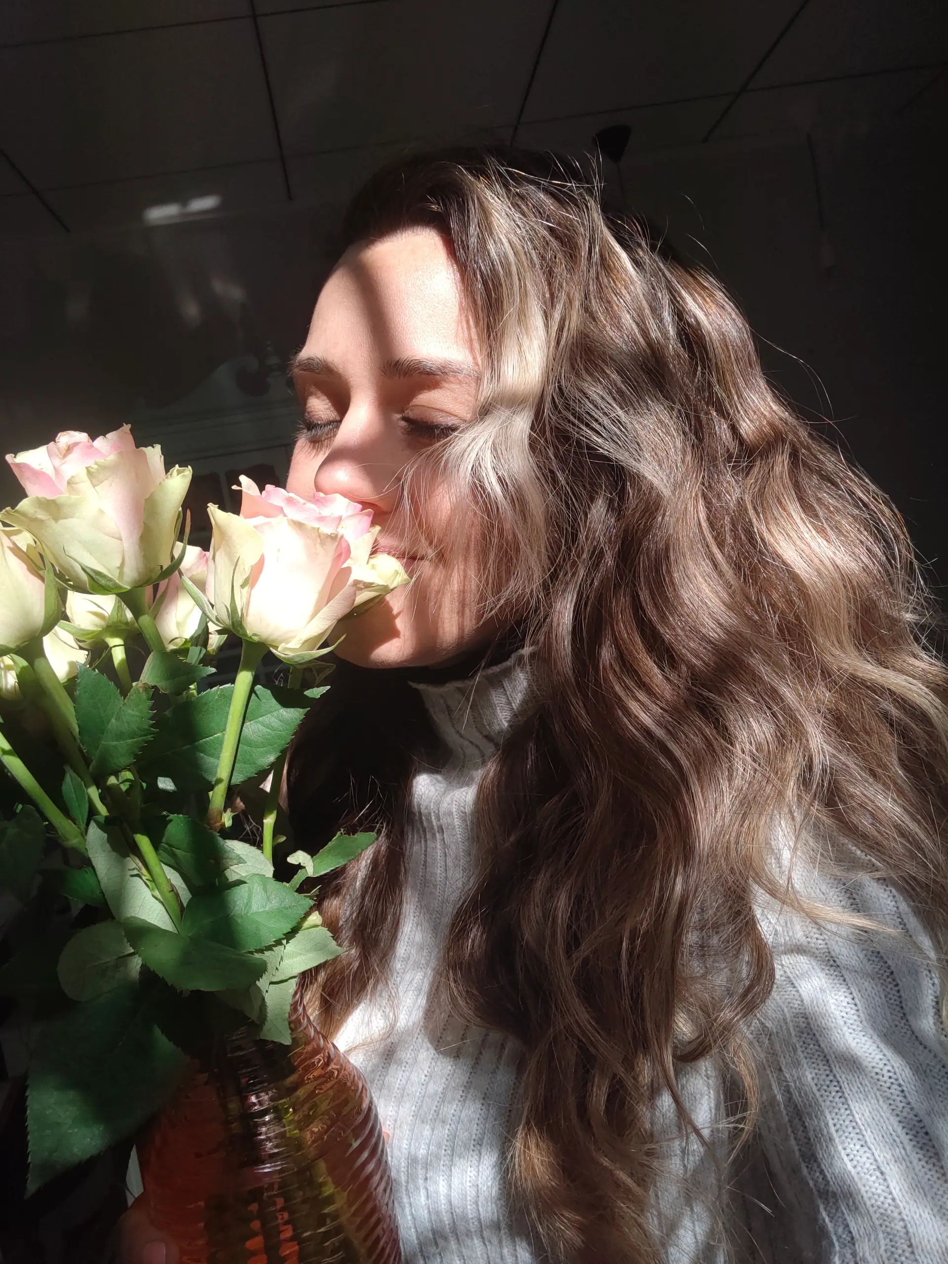 Alicia, fundadora de Con Cada Latido, oliendo un ramo de rosas bajo un rayo de sol
